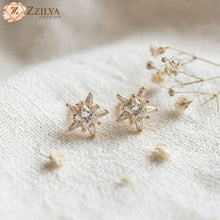 Star-shaped earrings on a textured surface with 'ZZILYA' branding.