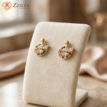 Swan earrings with colorful stones on a beige jewelry display stand, branded 'Zzilya Fashion'.