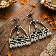 Ornate silver earrings with black and white stones on a wooden surface by Zzilya fashion.