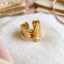 Gold ring on a textured surface with 'Zzilya' branding.