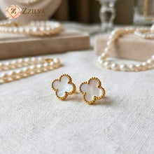 Gold and white flower-shaped earrings on a textured surface with 'Zzilya' branding.