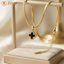 The Zzilya Fashion anti-tarnish golden snake chain necklace with a black onyx-style four-leaf clover pendant on a cream jewelry stand; affordable luxury piece showing high-quality craft.