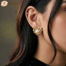 Close-up of a woman wearing a Zzilya Fashion golden anti-tarnish heart-shaped earring with a central pearl inlay and textured gold border, styled for office wear.