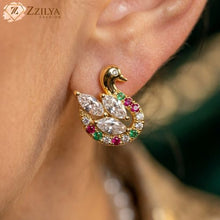 Close-up of a Zzilya Fashion golden anti-tarnish swan earring featuring marquise-cut white crystals on the wing and a colorful border of small red, green, and white stones.