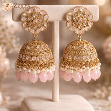 Exquisite gold-plated Jhumka earrings with pink stones, pearl detailing, and floral studs from Zzilya Fashion, displayed on a jewelry stand.