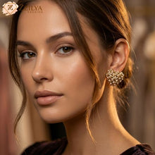 Close-up of a woman wearing gold heart pearl studded earrings with Zzilya Fashion logo.