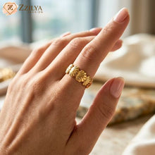 A wide golden anti-tarnish band ring featuring a repeating seashell or scalloped design worn on a person's finger, styled with a neutral manicure and soft-focus background for a clean-girl aesthetic by zzilya fashion