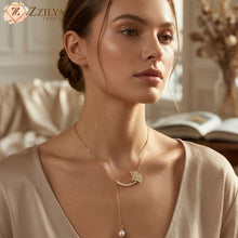 A woman wearing the Zzilya Fashion golden anti-tarnish lariat necklace featuring a crystal-studded ginkgo leaf pendant and a dangling pearl drop; elegant minimalist 2026 jewelry aesthetic.