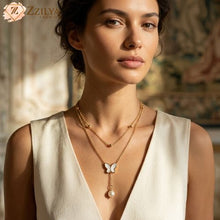 A woman wearing a Zzilya Fashion golden double-layer necklace; the top layer is a delicate gold bead chain, and the bottom layer features a white butterfly pendant with a dangling pearl drop against a white V-neck top.