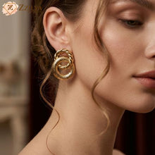 Close-up of a woman wearing gold hoop earrings with a blurred background by zzilya fashion