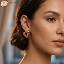 Close-up of a woman wearing gold heart-shaped earrings with 'Zzilya' branding.