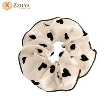 White scrunchie with black heart patterns on a white background, branded 'Zzilya'.