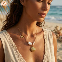A woman on a tropical beach wearing Zzilya Fashion's anti-tarnish golden necklace with a seashell pendant, a starfish charm, and baroque pearls; premium waterproof jewelry for 2026 beach aesthetics.