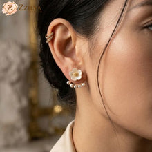 A delicate white flower stud featuring a shimmering golden center, paired with a trendy curved arc of pearls that hugs the earlobe